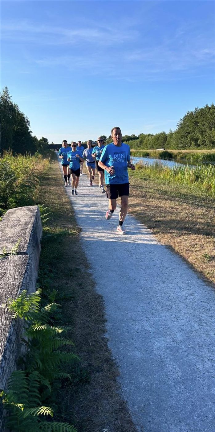 Groep hardlopers van de community run op een pad langs het water